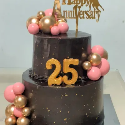 Celebrating a silver jubilee with this stunning two-tiered chocolate truffle cake. The rich chocolate base is decorated with pink and gold spheres and a "Happy 25th Anniversary" topper for a truly special milestone.