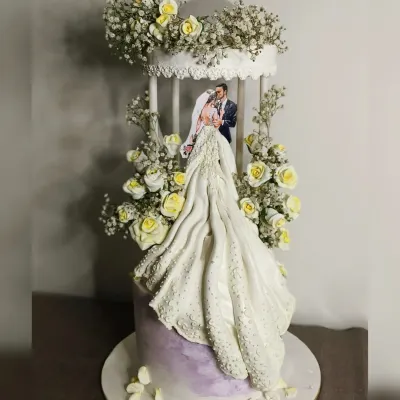 This wedding cake was a true showstopper. The design features a bride's gown flowing down the side of the cake, complete with intricate textures and sparkle. Housed within a delicate birdcage structure and adorned with fresh baby's breath, it's a cake that tells a romantic story.