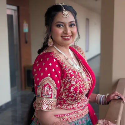 A radiant Gujarati bride on her wedding day. I created a classic bridal look with defined eyes, a bold red lip, and glowing skin to complement her stunning red and teal lehenga.