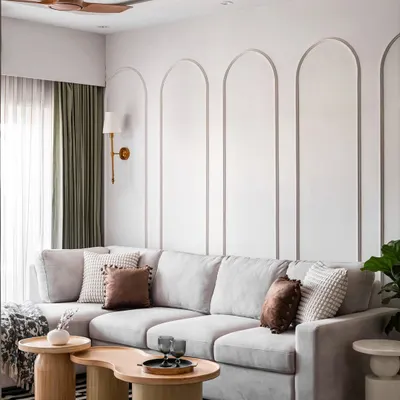 We designed this luxurious living room with a focus on creating a serene and sophisticated atmosphere. The large, comfortable L-shaped sofa is perfect for family time, and the wall is adorned with elegant arched mouldings. The organic-shaped wooden coffee tables and a striped rug add texture and warmth to the space.