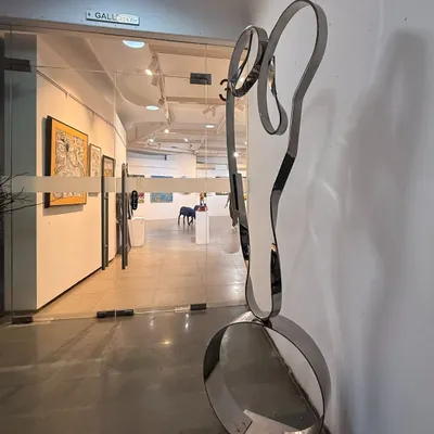"The Bond," a freestanding sculpture in stainless steel, seen here at the entrance to a gallery. Its form is an abstract representation of a mother and child's embrace.