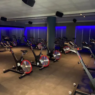 For the Chakra spinning studio, we created a high-energy, immersive environment. The use of dynamic blue ambient lighting against dark walls and industrial-style flooring sets a motivational tone for intense workouts.
