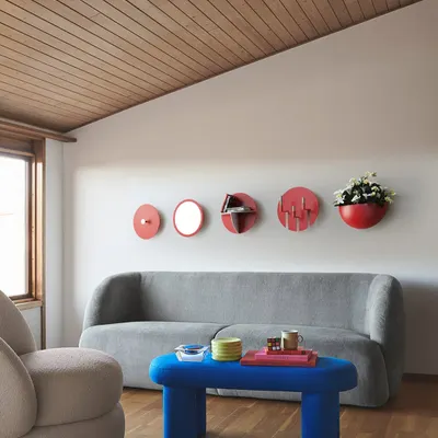 The Aabhla collection shown as a vibrant wall installation. The composition of red and blue circular forms, including a mirror, shelves, and a wall planter, creates a playful and artistic statement piece inspired by Indian craft.