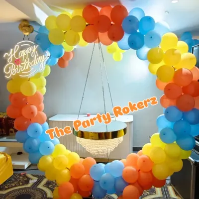 A colorful balloon ring with a hanging chandelier-style cake table. This is a unique and elegant way to display the birthday cake and serves as a fantastic photo backdrop.