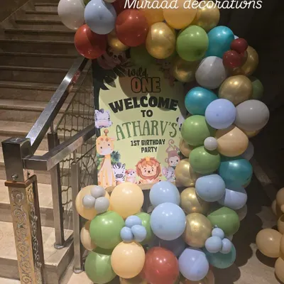 A welcoming entrance for a jungle-themed first birthday party. This balloon semi-arch is filled with colorful balloons and features a sign with cute jungle animals to greet the guests.