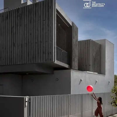 The facade of 'Maya House' is defined by its clean lines and the texture of the vertical Sadarhalli stone fins. This material choice is not just aesthetic; it helps regulate the light entering the south-facing home.