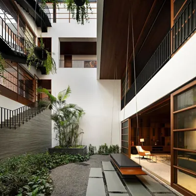 This central courtyard is designed as an open-to-sky sanctuary within the home. The use of gravel, stone pavers, and a mix of hanging and potted plants creates a multi-layered green space that connects different levels of the house.