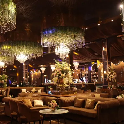 A wide view of a magnificent event hall I catered. The combination of lush floral chandeliers, comfortable lounge seating, and ambient lighting creates an immersive and high-end atmosphere for guests.