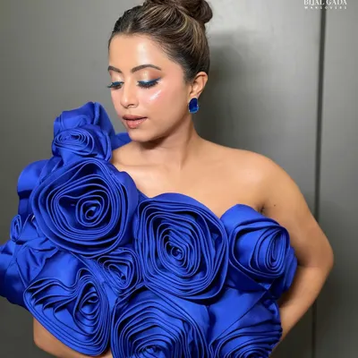 A close-up of the modern glam look, highlighting the flawless glass skin and the pop of blue from the winged eyeliner. The sleek high bun adds a touch of sophistication to the overall style.