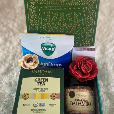 When someone you care about is feeling under the weather, a thoughtful care package can make all the difference. This simple yet effective get well soon hamper includes Vahdam green tea, sugar-free Badamika sweets, and Vicks cough drops.