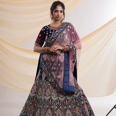 A breathtaking navy blue velvet lehenga with intricate multi-color embroidery and a contrasting pink dupatta. This is a perfect choice for a bride or for attending a wedding.