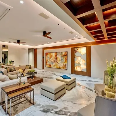This living room is a masterclass in balancing scale and comfort. We used a coffered wooden ceiling to add warmth and architectural interest, while the expansive Satvario marble flooring provides a luxurious foundation for the neutral-toned, plush furniture.