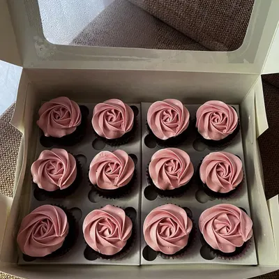 A box of my classic chocolate cupcakes with a pretty pink whipped cream frosting. I pipe each rosette by hand, making them a beautiful and delicious choice for parties, gifts, or just because.