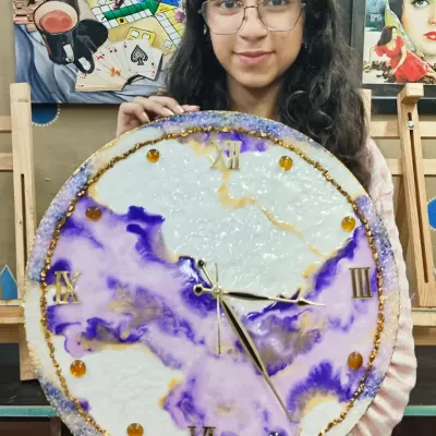 A talented student showcasing her magnificent resin art clock. Our workshops guide you through the entire process, from mixing colors to adding details like clock hands and numbers.