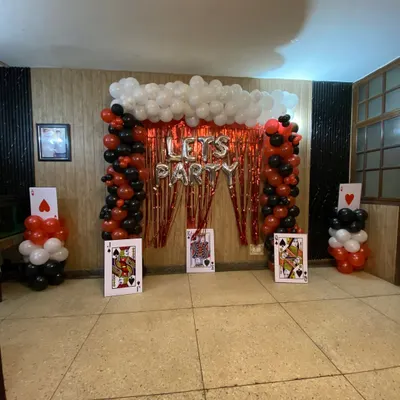 I can create fun, themed party setups like this casino or card party decoration. This design includes balloon pillars, a red tinsel curtain backdrop, 'LET'S PARTY' foil balloons, and large playing card props to complete the look.