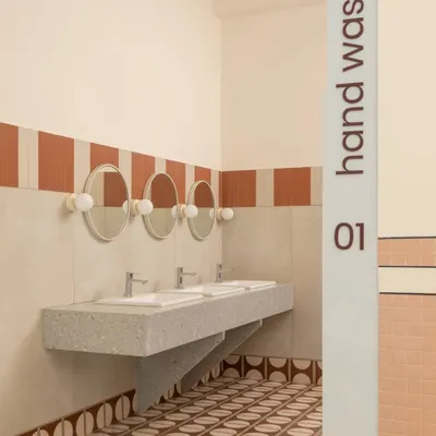 The hand wash station adjacent to the dining hall is clean, functional, and fun. We used patterned floor tiles and a striped wall detail to add a pop of color and personality to this practical space.