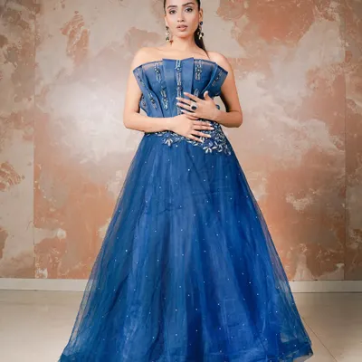 A classic portrait of elegance in a stunning royal blue ball gown. The studio lighting is crafted to highlight the texture of the denim-style corset and the shimmering tulle skirt, creating a look of modern royalty.