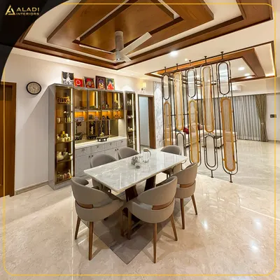 An open-plan living and dining area designed for seamless interaction. The space features a marble-top dining table, a glass-encased crockery unit, and a decorative partition that elegantly separates the dining area from the living room.