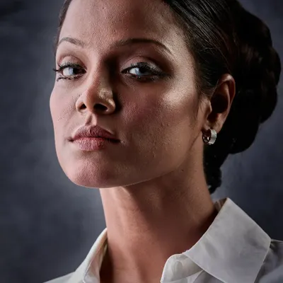 A powerful, high-contrast portrait. In black and white, the focus is on the sculpted features, the intense gaze, and the clean, classic updo. The makeup is designed to define and shape, even without color.