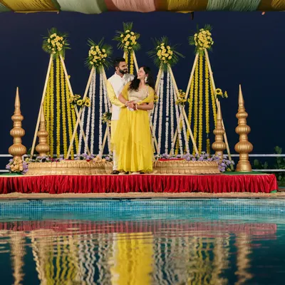 A stunning Haldi portrait by the pool at night. The reflection in the water and the beautifully lit decor create a magical and romantic atmosphere for the couple.