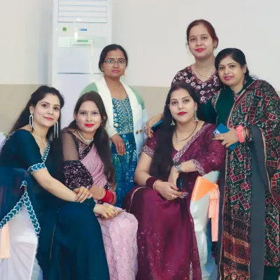 A group of female guests dressed in elegant sarees and suits posing together at a party.