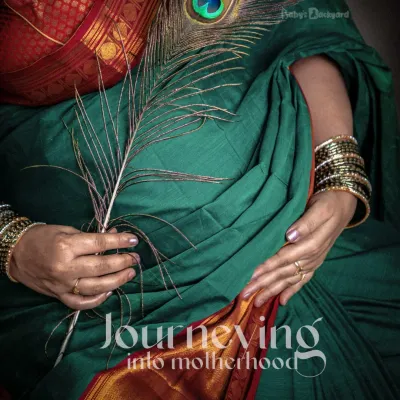 Journeying into motherhood, wrapped in the elegance of a traditional green saree. This close-up shot with a peacock feather beautifully symbolizes grace and new beginnings.
