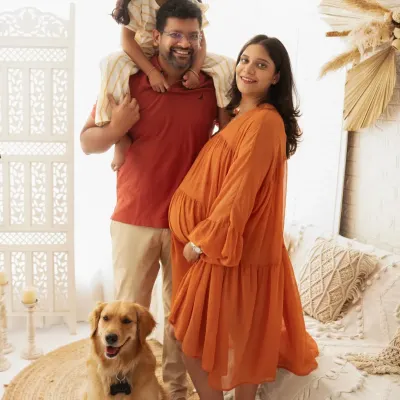A fun and joyful family portrait. With the older sibling on dad's shoulders and the family dog by their side, this photo is full of life and happiness.