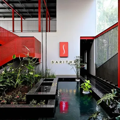 The central atrium of the SARITHA SERENE marketing office is a vibrant and dynamic space. We used a bold red for the structural steel elements, contrasting with the tranquility of the indoor water body and lush planters to create a memorable first impression.