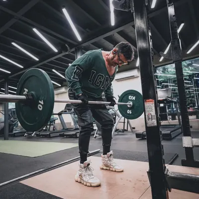 Capturing the grind of a workout. This fitness lifestyle shot focuses on the subject's form during a barbell row, using the gym's ambient lighting to create a raw, motivational atmosphere.