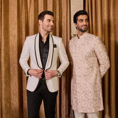 Showcasing the versatility of my collections, this image pairs a classic white tuxedo with a contemporary embroidered Indo-Western sherwani. Whether your style is ethnic or western, I can create a coordinated look for you and your groom squad.