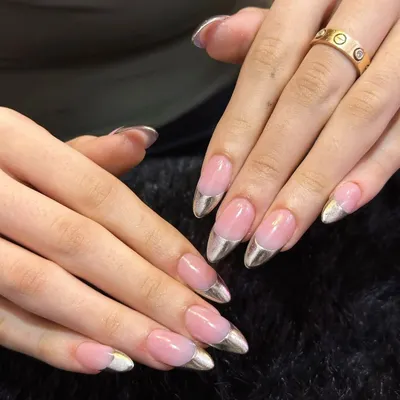 A futuristic take on a classic. These almond-shaped nails feature a flawless nude base with gleaming silver chrome tips. This chrome French manicure is perfect for a sleek, modern, and high-fashion look.