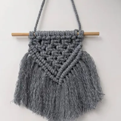 This small macrame wall hanging is perfect for adding texture and a bohemian feel to a gallery wall or a small nook. The intricate knots and soft fringe are all done by hand.