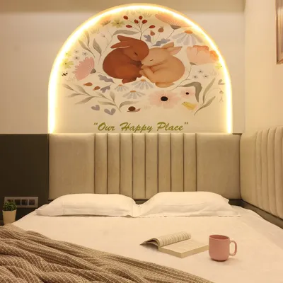 A charming bedroom design featuring a custom arched mural with integrated backlighting above the bed. The soft, upholstered headboard and the "Our Happy Place" text create a personalized and comforting atmosphere.