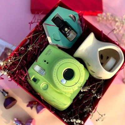 A perfect Valentine's gift for creating memories. This hamper features a bright green Instax Mini camera, an essential oil diffuser, and fragrant diffuser oil, all nestled in a vibrant red gift box.