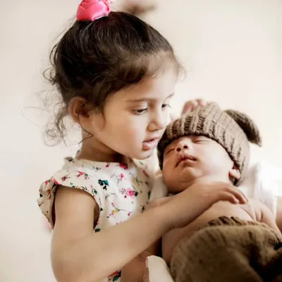 The first meeting between siblings is a moment to treasure forever. Here, a big sister gently holds her newborn brother, a beautiful memory captured during our in-home newborn session.