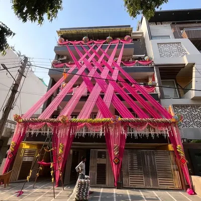 This is an example of a full house exterior decoration to create a festive wedding atmosphere. I used long pink fabric drapes crisscrossing the building's facade, anchored with floral arrangements, to make the home stand out for the pre-wedding functions.