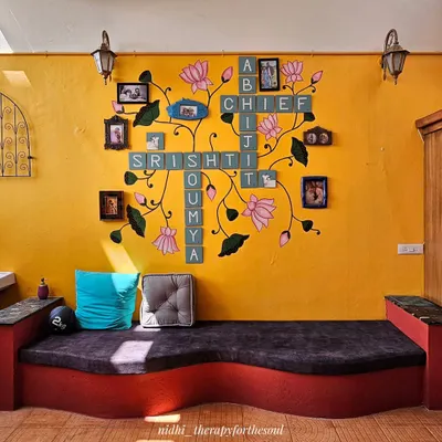 The finished Scrabble and Pichwai wall art in its home. The design combines the family's names with flowing lotus vines and integrates their photo frames, creating a truly personal art installation.