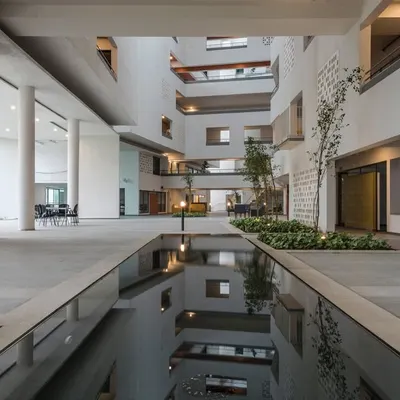 The central atrium at Parkside Retirement Homes, featuring a water body that reflects the multi-level structure. This space is the social heart of the building, connecting various activity zones and providing a serene environment for residents.