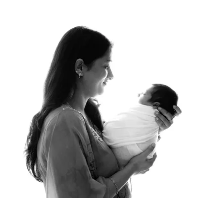 A tender black and white silhouette of a mother gazing at her newborn. This artistic shot focuses on the emotional bond and the quiet, loving moments right after birth.