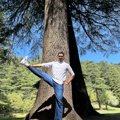 Practicing Utthita Hasta Padangusthasana (Extended Hand-to-Big-Toe Pose) next to a magnificent Deodar tree in Khajjiar, the mini Switzerland of India.