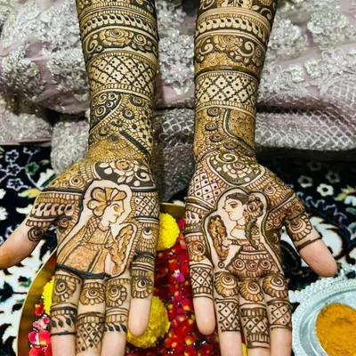 A close-up shot of the classic bride and groom portrait henna. This view highlights the shading and fine details that bring the figures to life on the palms.