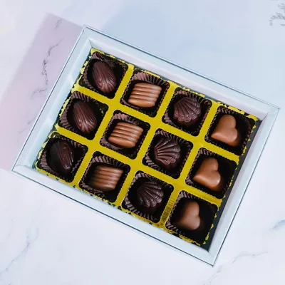 A top-down view of my 12-piece praline collection, showcasing the variety of shapes and flavors. You can see heart-shaped milk chocolates, shell-shaped dark chocolates, and more.