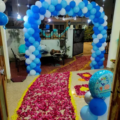 A classic 'Welcome Baby Boy' entrance decoration. We created a blue and white balloon arch over the doorway and a rose petal carpet to make the arrival feel extra special.