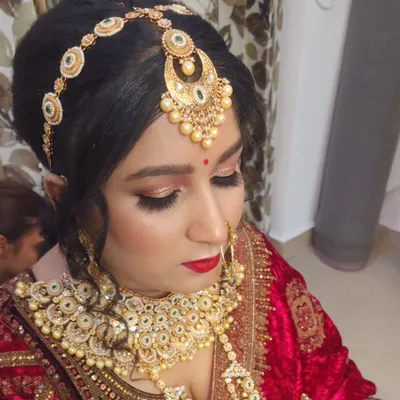 A close-up of a stunning Rajputana bridal look. The focus is on the elaborate matha patti, the classic red lip, and the shimmering eye makeup that defines this royal style.