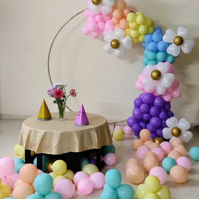 A creative and whimsical balloon arrangement featuring a half-arch of pastel balloons shaped into flowers.
