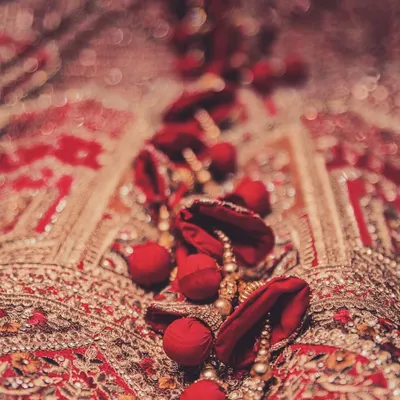 Beauty is truly in the details. This close-up macro shot highlights the intricate red embroidery and beadwork on a bride's wedding lehenga, a testament to the craftsmanship involved.