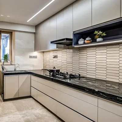 A sleek, modern kitchen with handleless beige cabinets, a black granite countertop, and a geometric tile backsplash. Integrated LED strip lighting under the cabinets illuminates the workspace.