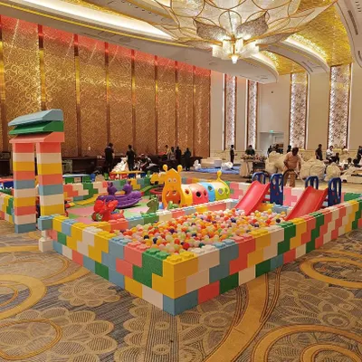 This is our signature Lego Land play area, set up in a large event hall. It provides a complete, enclosed environment with a ball pit, slides, and soft flooring, allowing kids to play freely and safely.