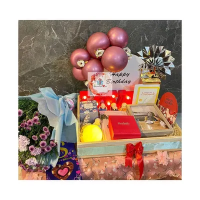 An elaborate birthday tray hamper featuring a pink balloon arrangement, a bouquet of fresh flowers, and a curated selection of gifts including a framed photo and other personal touches.