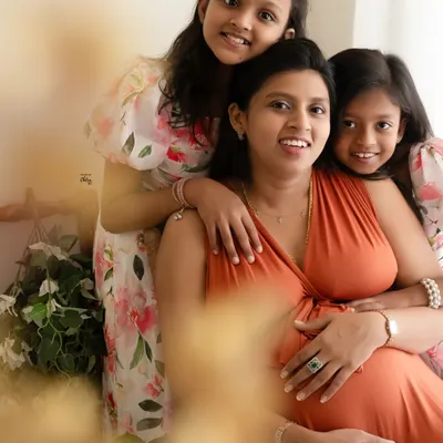A beautiful family portrait full of love. The daughters embracing their mother creates a heartwarming image of their special bond as they await the new arrival.
